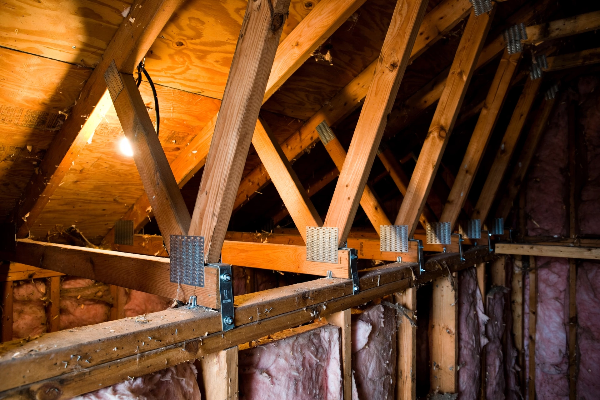 Roof-to-wall hurricane straps photographed in an attic